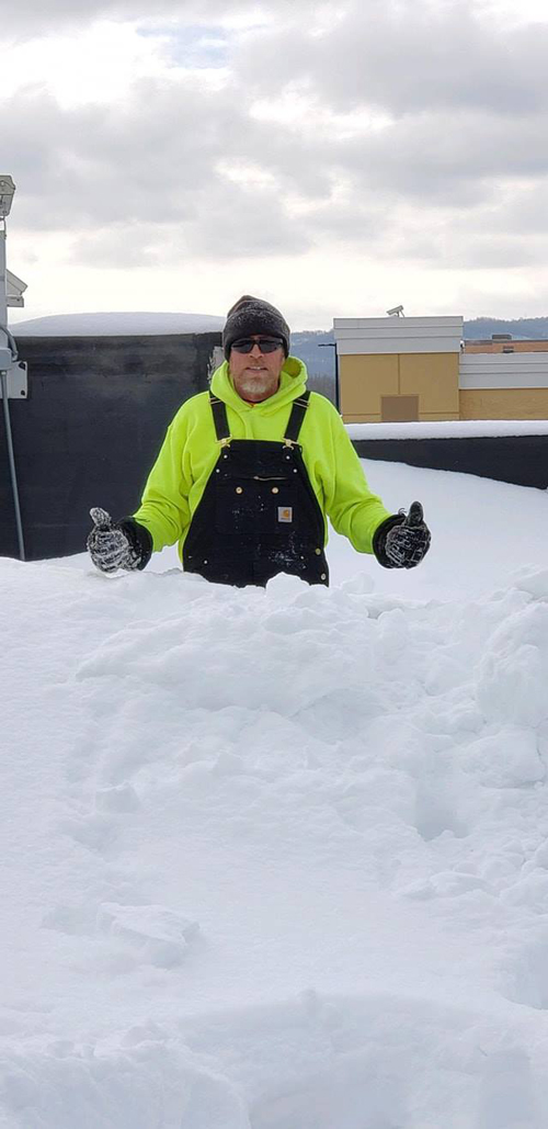 A Ledegar Roofing employee standing on a commercial roof, waist deep in snow!